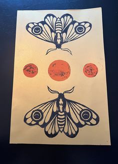 an orange and black moth on a white paper with three red circles in the background