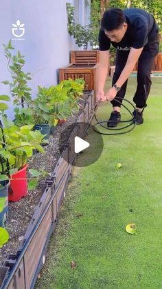 a man using a garden hose to water plants