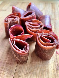 several pieces of raw meat on a cutting board with one cut in half and the other rolled up