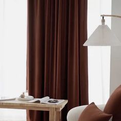 a living room scene with focus on the curtained window and coffee table in the foreground