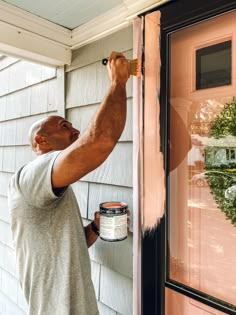 a man painting the side of a house with pink paint on it's front door