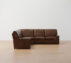 a brown leather couch sitting on top of a hard wood floor next to a white wall