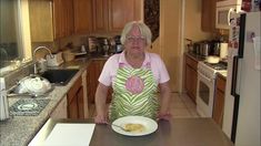 an older woman is holding a plate with food on it in the middle of a kitchen