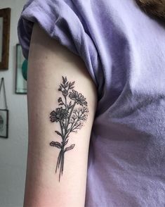 a black and white flower tattoo on the left upper arm, with leaves in it