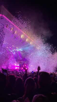 the crowd is watching fireworks and confetti being thrown into the air at an outdoor concert