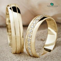 two gold wedding rings with diamonds on the inside and outside, sitting next to each other