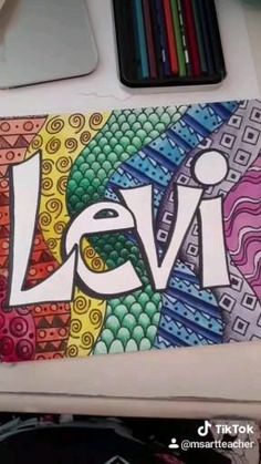 the word levi is painted on a piece of paper with colored pencils next to it