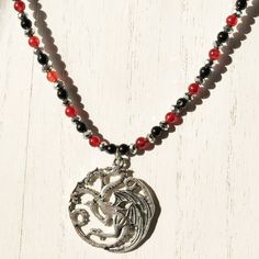 Be the Mother of Dragons with this Game of Thrones necklace featuring the House Targaryen three-headed dragon sigil. Perfect for finishing out your Halloween or cosplay costume. Includes FREE gift bag. Adjustable Fantasy Necklaces For Fantasy Events, Adjustable Fantasy Necklace For Fantasy Events, Fantasy Pendant Necklace For Cosplay, Adjustable Gothic Beaded Necklace As Gift, Adjustable Gothic Beaded Necklace For Gift, Adjustable Fantasy Necklaces For Cosplay, Mystical Adjustable Necklace With Round Beads, Adjustable Mystical Necklace With Round Beads, Halloween Silver Jewelry With Round Beads