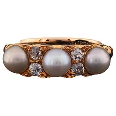 a gold ring with three pearls and diamonds on it's sides, set against a white background