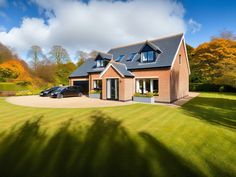 a car parked in front of a house on a lush green field next to trees