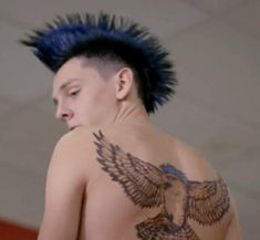 a man with blue hair and an eagle tattoo on his back