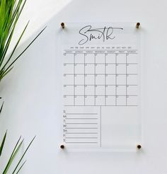 a calendar hanging on a wall next to a plant