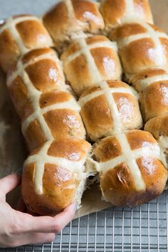 hot cross buns on a cooling rack being held by someone's left hand