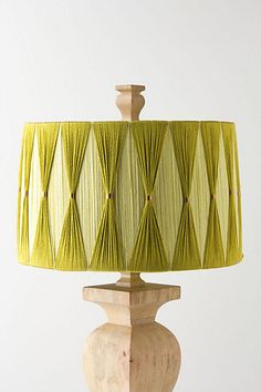 a green lamp shade sitting on top of a wooden table next to a white wall