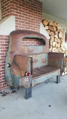 an old rusted out car sitting on top of a wooden bench next to a pile of logs