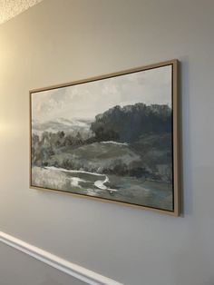 a painting hanging on the wall above a fireplace in a room with white walls and wood trimmings