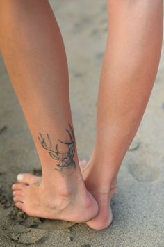 a close up of a person's foot with a deer tattoo on the side