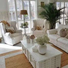 a living room filled with white furniture and lots of pillows on top of it's couches