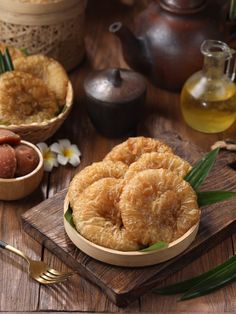 some food is on a wooden table with other foods in bowls and spoons next to it