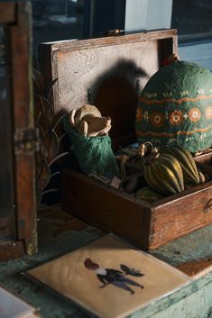 an old wooden box filled with assorted items on top of a table next to a window