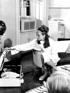 a woman sitting on the floor in front of a box filled with food and balloons