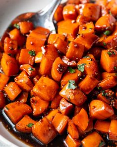 a white bowl filled with cooked carrots and sauce