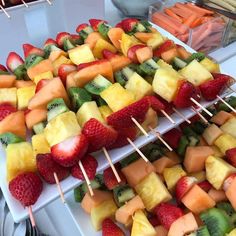 fruit skewers are arranged on trays with forks