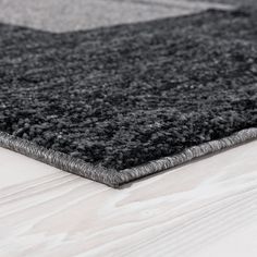 a black and grey rug on top of a wooden floor