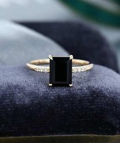 a black diamond ring sitting on top of a velvet cushion