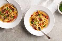 two white bowls filled with pasta on top of a table