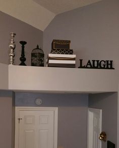 there is a shelf above the door with books and other items on top of it