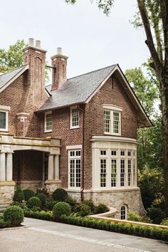 a large brick house with white trim and two chimneys on the top of it's roof