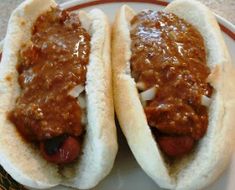 two hot dogs on buns covered in chili