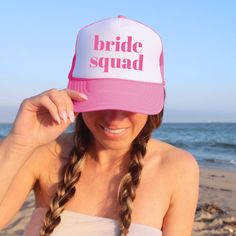 a woman wearing a pink and white bride squad hat