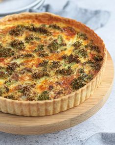 a quiche with broccoli and cheese on a wooden platter