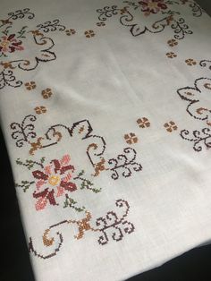 an embroidered table cloth with flowers and leaves