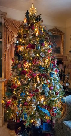 a brightly colored christmas tree in a living room decorated for the holiday season with ornaments and lights