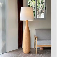 a lamp that is sitting next to a couch in a room with a chair and window