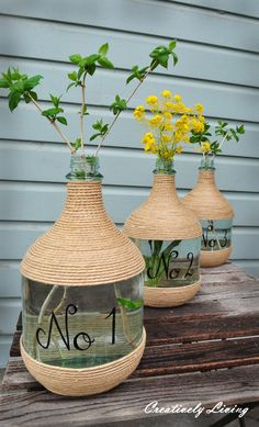 three vases with flowers in them sitting on a wooden table next to a house