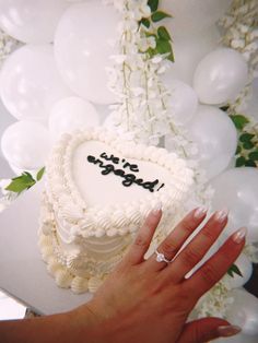 a woman's hand holding a white cake with the word love spelled on it