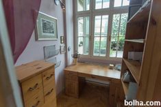 a wooden desk sitting next to a window in a room