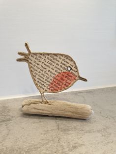 a small wooden bird sitting on top of a piece of wood