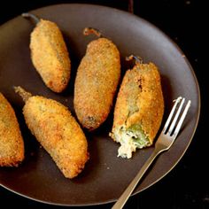 four fried food items on a plate with a fork