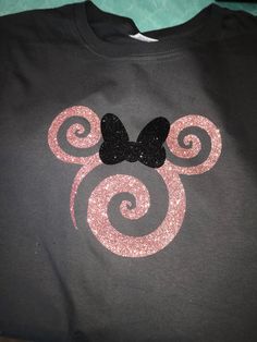 a mickey mouse shirt with pink and black glitters on the front, which is shaped like a swirly bow