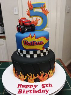 a birthday cake for a five year old boy with monster trucks on top and flames