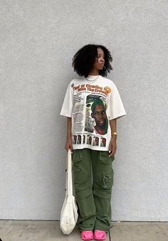 a woman standing in front of a wall holding a tennis racket and t - shirt