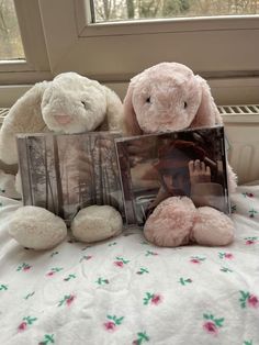 two stuffed animals sitting on top of a bed next to an album and teddy bear