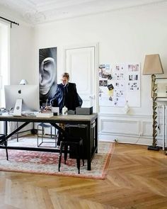 a man is sitting at his desk in the middle of a room with wood floors