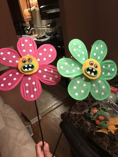 two paper flowers with faces painted on them