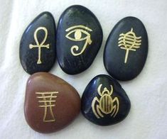 four different types of rocks with symbols painted on them, all in gold and black